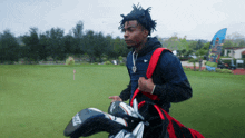a man is carrying a bag of golf clubs with a titleist head cover on it