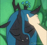 a hand is touching a cartoon character 's head with a crown on her head .