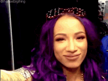 a woman with purple hair is taking a selfie with sunglasses on her head .