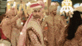 a man in a turban is standing in a crowd of people at a wedding .