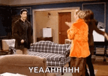 a group of people are standing in a living room with a plaid couch .