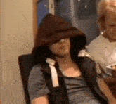 a man wearing a hoodie is sitting in a chair .
