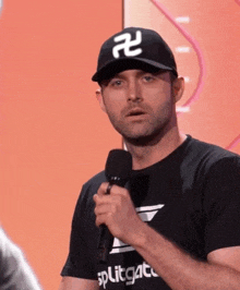 a man wearing a hat and a black shirt is holding a microphone in his hand .