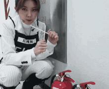 a woman is kneeling next to a fire extinguisher
