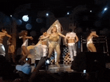 a group of people are dancing on a stage with a man taking a picture with his phone