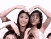 a group of young women are making a heart with their hands .