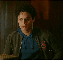 a young man with curly hair is sitting at a table with a plate of food .