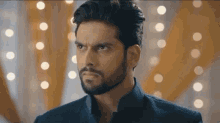 a man with a beard is looking at the camera with a serious expression on his face .