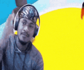 a man wearing headphones and a bandana is standing in front of a yellow background