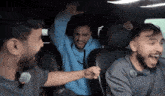 a group of men are sitting in the back seat of a car laughing .