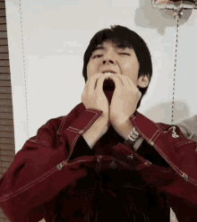 a man wearing a maroon jacket with a watch on his wrist makes a funny face