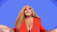 a woman in a red jacket is standing in front of an american flag and making a funny face .