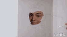 a person is painting a woman 's face with a brush and the words made in animotica on the bottom