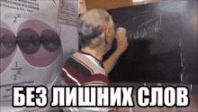 a man is writing on a blackboard with russian writing on it .