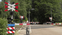 a red white and blue railroad crossing with a sign that says ' wacht het niet tot gebroken is '