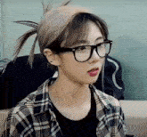 a young woman wearing glasses and a plaid shirt is making a funny face .