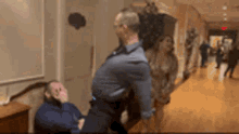 a man in a suit is standing next to another man in a hallway
