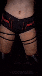 a woman 's stomach is shown in a black top and red shorts