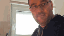 a man wearing glasses and a black hoodie looks at the camera