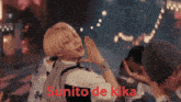 a man wearing a wristband that says ny on it stands in front of a sign that says sunito de kika