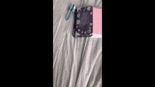 a pink book is laying on a bed next to a cell phone