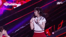 a woman in a red skirt and white shirt is dancing on a stage in front of a crowd .