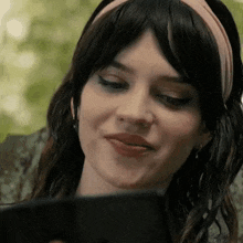 a woman wearing a headband is looking at her phone .