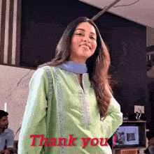 a woman in a green dress stands in front of a thank you sign