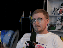 a man wearing glasses is talking into a microphone with a sticker that says 0000 on it
