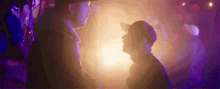 a man and a boy are standing next to each other in a dark room with purple lights .