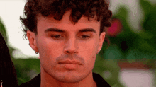 a close up of a man 's face with curly hair and ear piercings