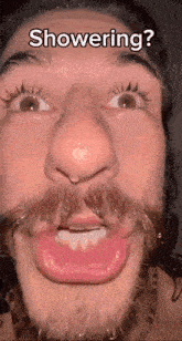 a man with a beard and mustache is making a funny face while showering .