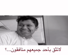 a man is smiling in a black and white photo with arabic writing below him