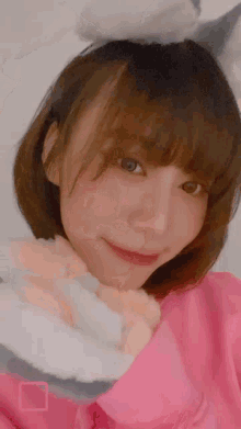 a woman wearing a pink sweater and bunny ears