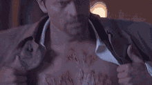 a man is holding his shirt open to reveal a scar on his chest .