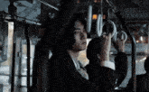 a man in a suit and tie is holding onto a railing on a bus