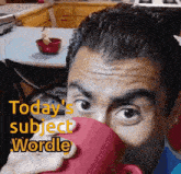 a man is drinking a cup of coffee in a kitchen while looking at the camera .