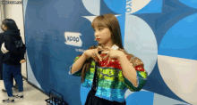 a woman making a heart shape with her hands in front of a kpop sign