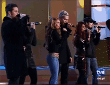 a group of people singing in front of a sign that says tve rbd.gif