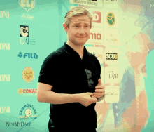 a man stands in front of a wall with logos such as filq and chupa chips on it