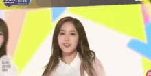 a woman in a white shirt is standing in front of a colorful background on a television screen .