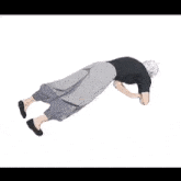 a man in a black shirt and gray pants is doing a handstand .