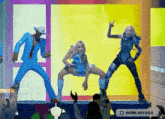 a man in a blue suit and a woman in a blue dress are dancing on a stage in front of a crowd .