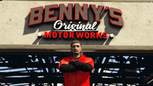 a man in a red jacket stands in front of a benny 's original motor works sign