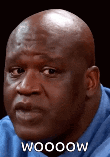 a bald man is wearing a blue shirt and says woooow
