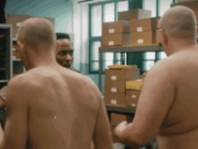a group of naked men are standing in a room with boxes
