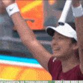 a woman wearing a nike wristband is holding a tennis racquet in her hands