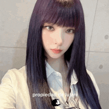 a woman with long purple hair is taking a selfie with the words propiedad de lujan above her