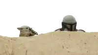 a man in a helmet looks over a sandy hill at a baby