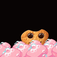 a cookie with big eyes is surrounded by pink soaps